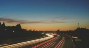 streaks of car tail lights on highway during sunset