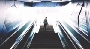 man standing at top of stairs looking up at light