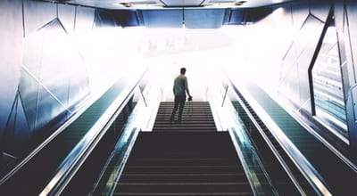 man standing at top of stairs looking up at light