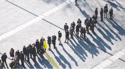 woman in yellow coat standing out in line of people