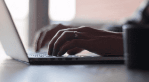 pair of hands typing on a laptop