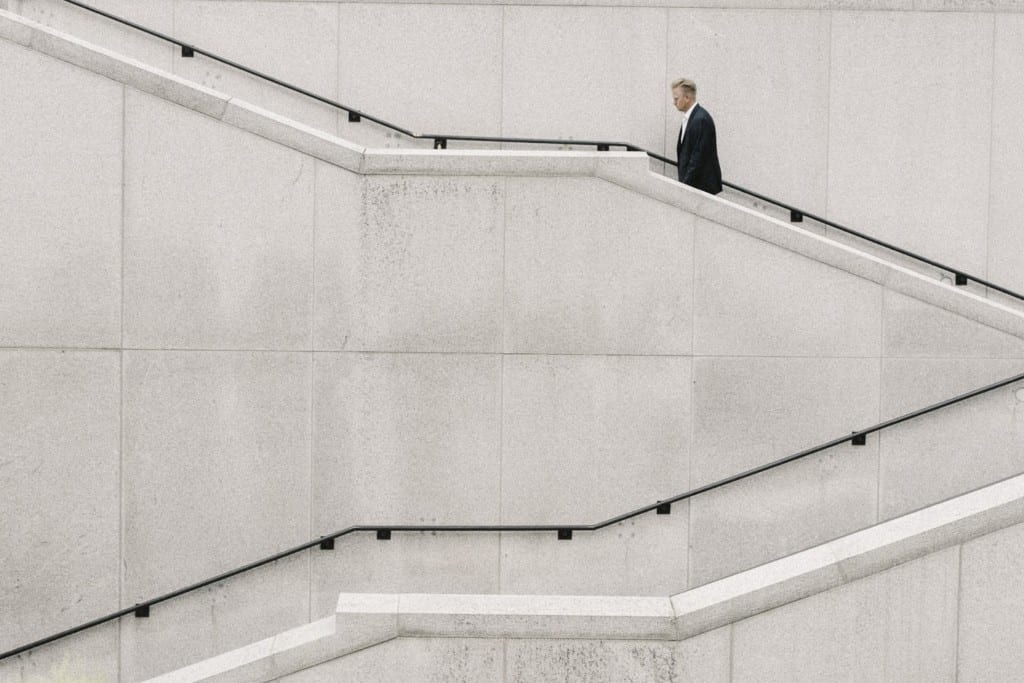 man walking up two flights of cement stairs